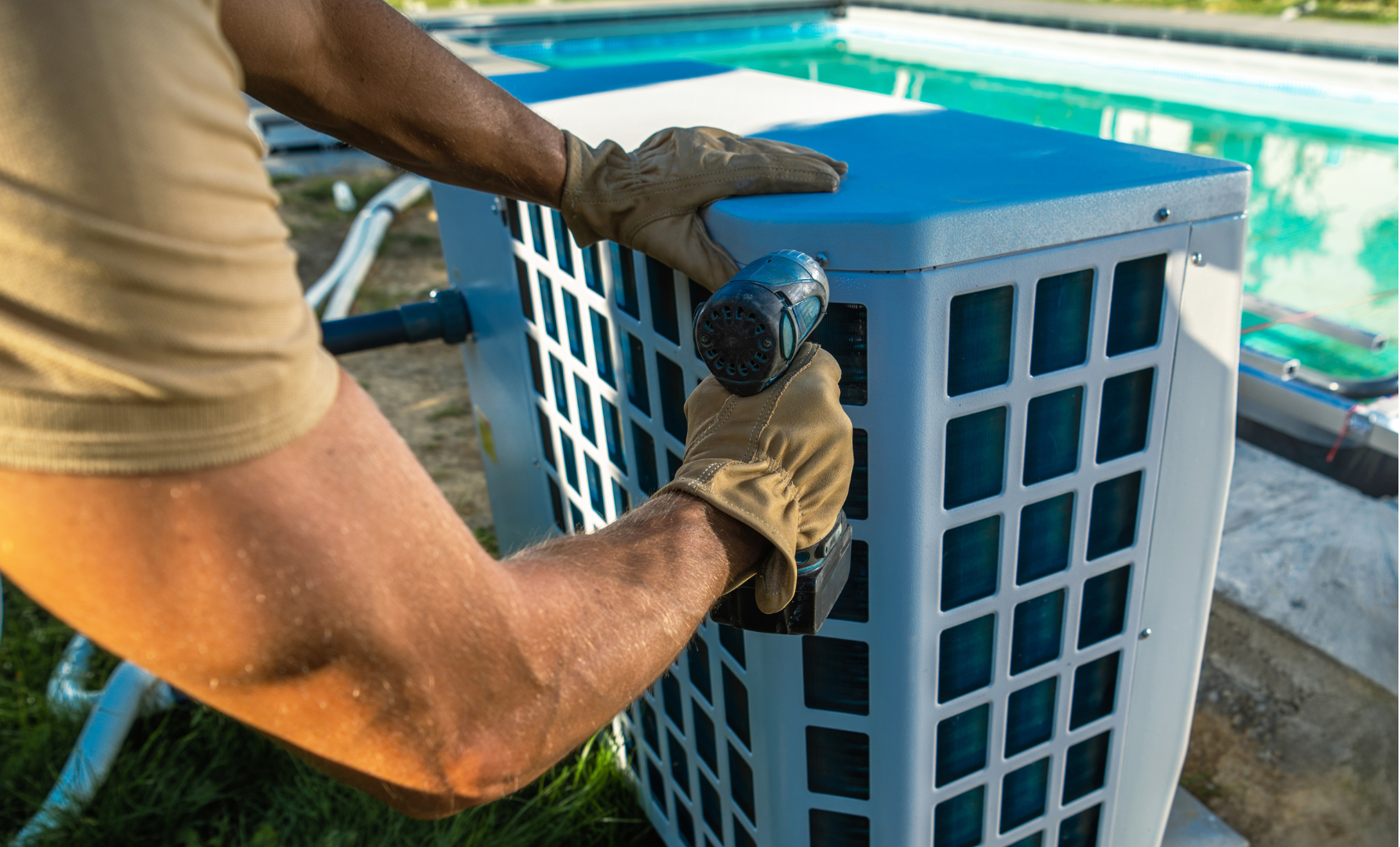 A man is working on an air conditioner next to a swimming pool.