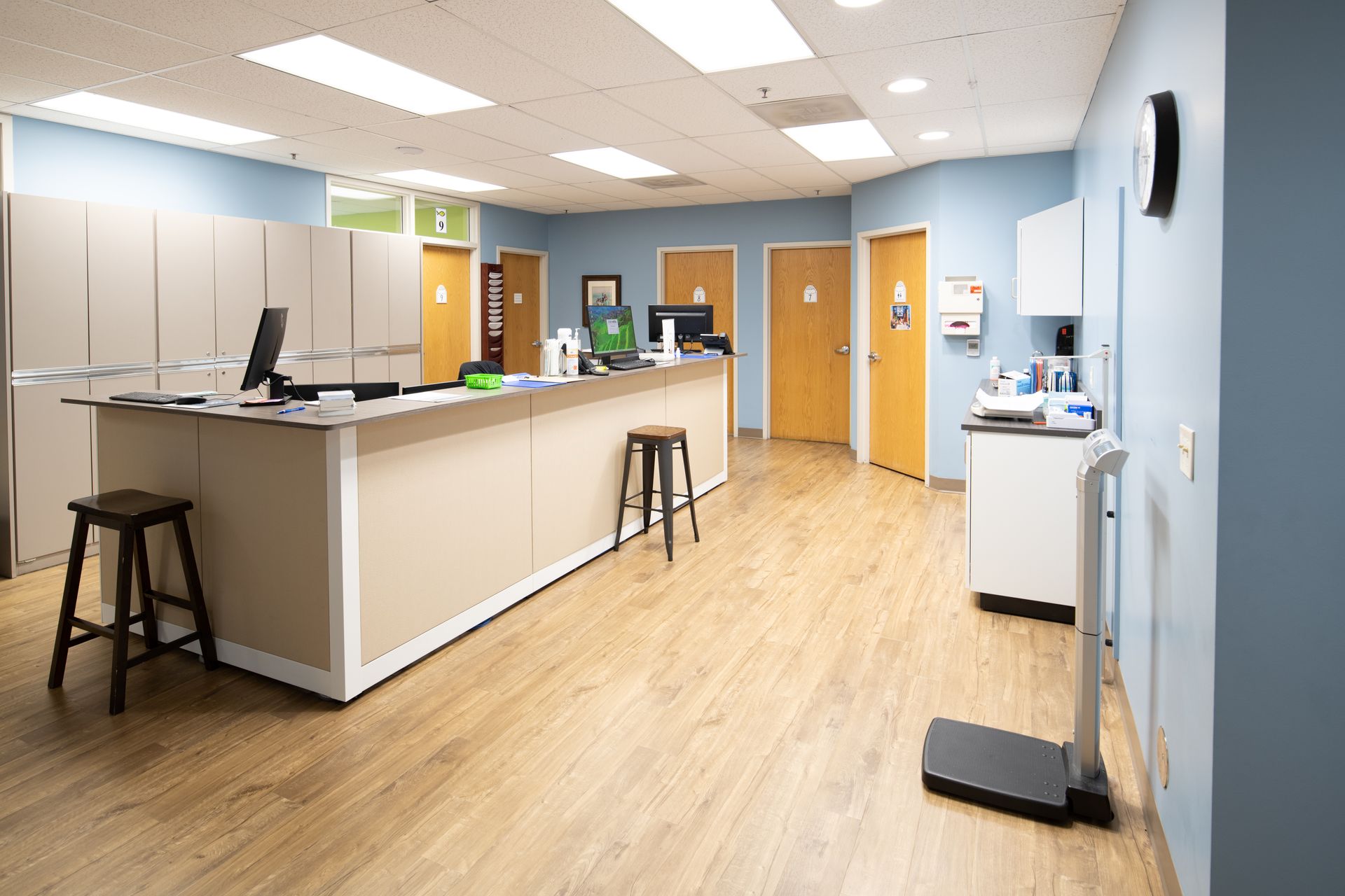 Interior of a medical office, with light wood floors, blue walls, and a reception desk.
