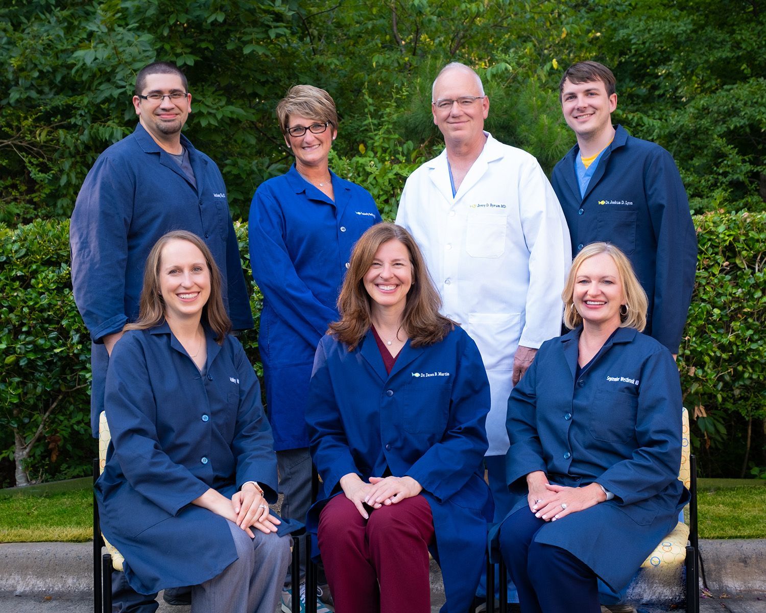 Group of medical professionals wearing lab coats posing outdoors for a photo.