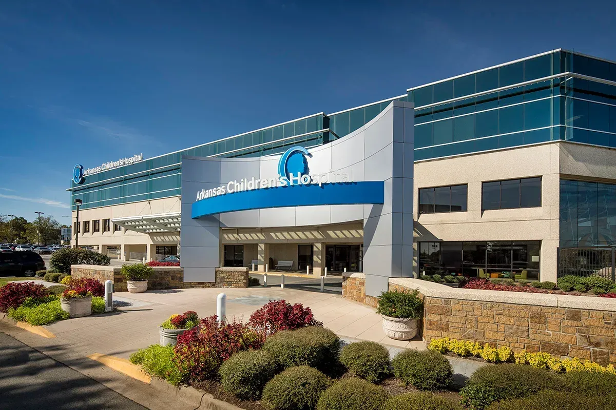 Entrance to Stone Rehabilitation & Health Center. Blue sign and building with landscaping, sunny day.