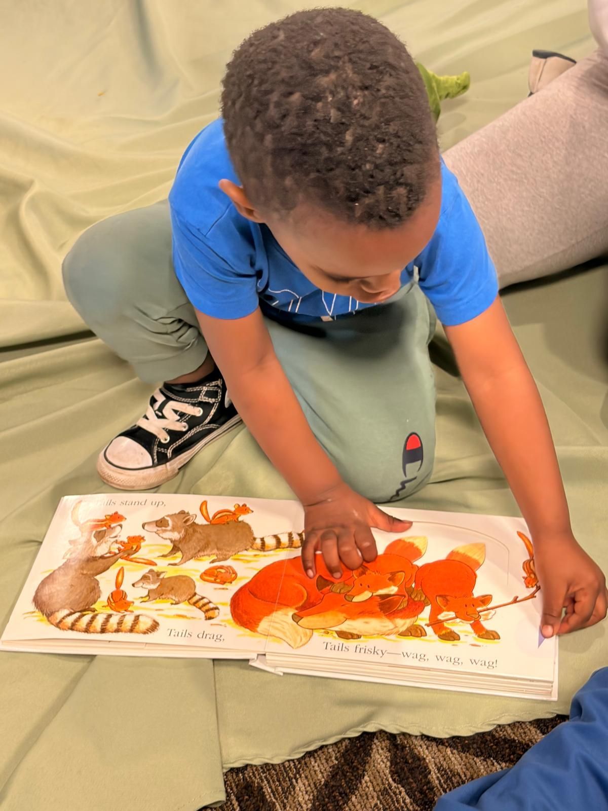 Child kneeling on a couch, placing pieces on a colorful animal puzzle book.