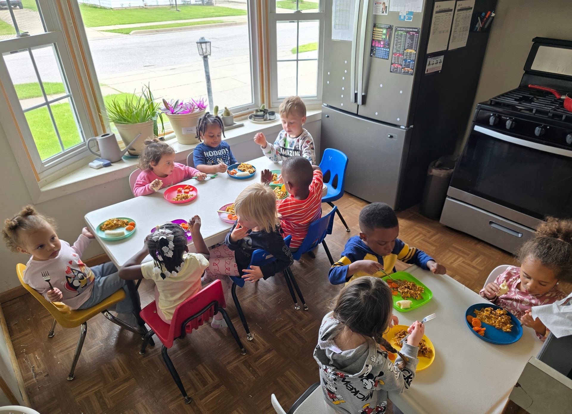 A smiling child sits at a table in a classroom, holding a yellow apple with various fruits nearby.