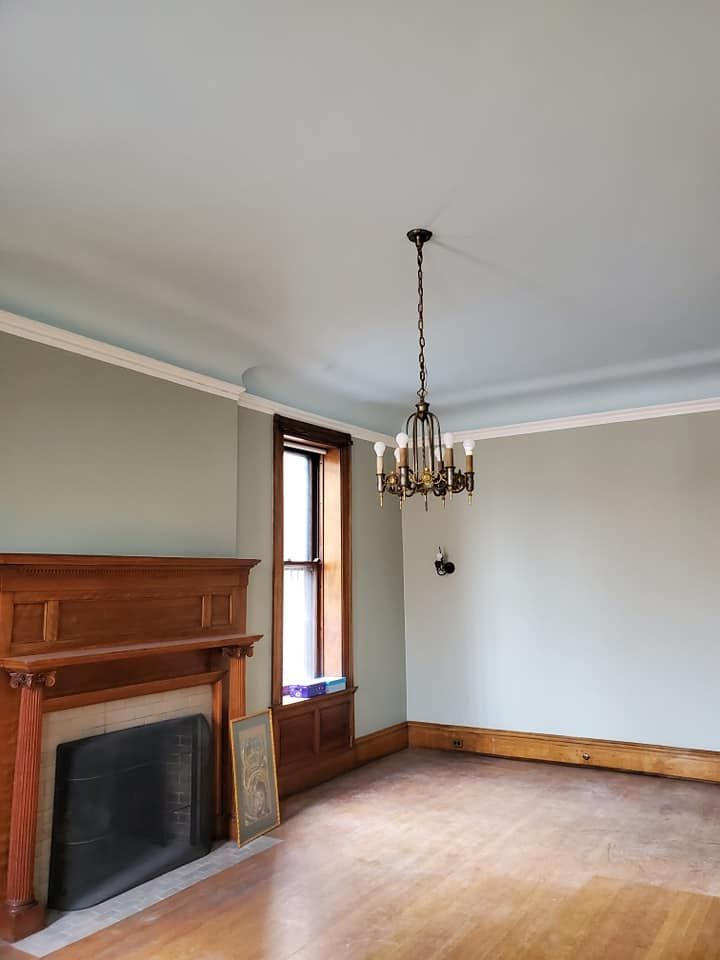 An empty living room with a fireplace and a chandelier hanging from the ceiling.