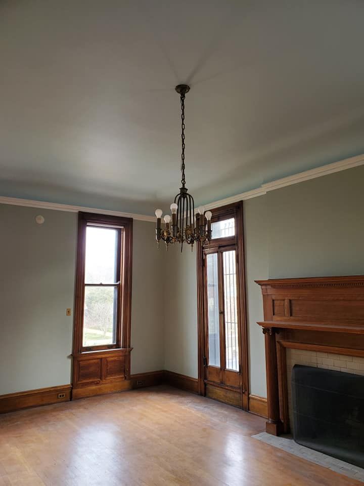 An empty living room with a fireplace and a chandelier