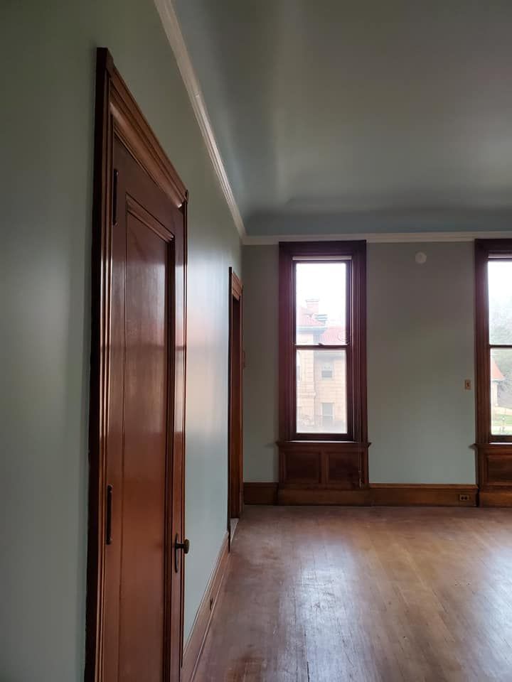 A large empty room with hardwood floors and two windows.