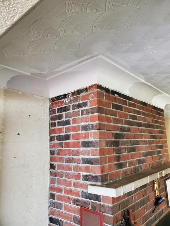 A brick fireplace with a white ceiling in a living room.
