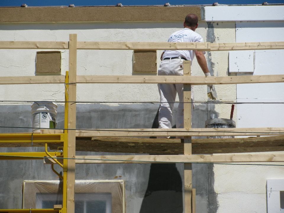 A man is standing on a scaffolding painting a building