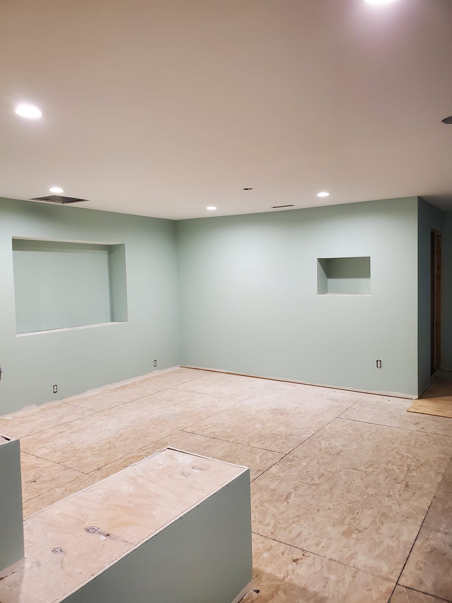 An empty room with green walls and a wooden floor.