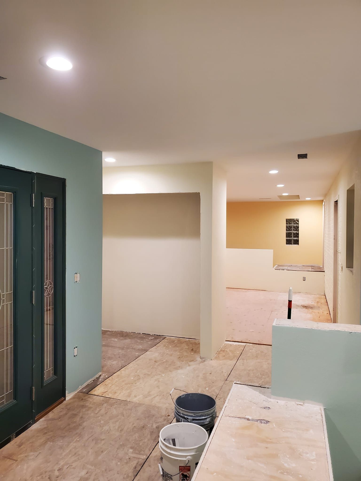A hallway in a house under construction with buckets of paint on the floor.