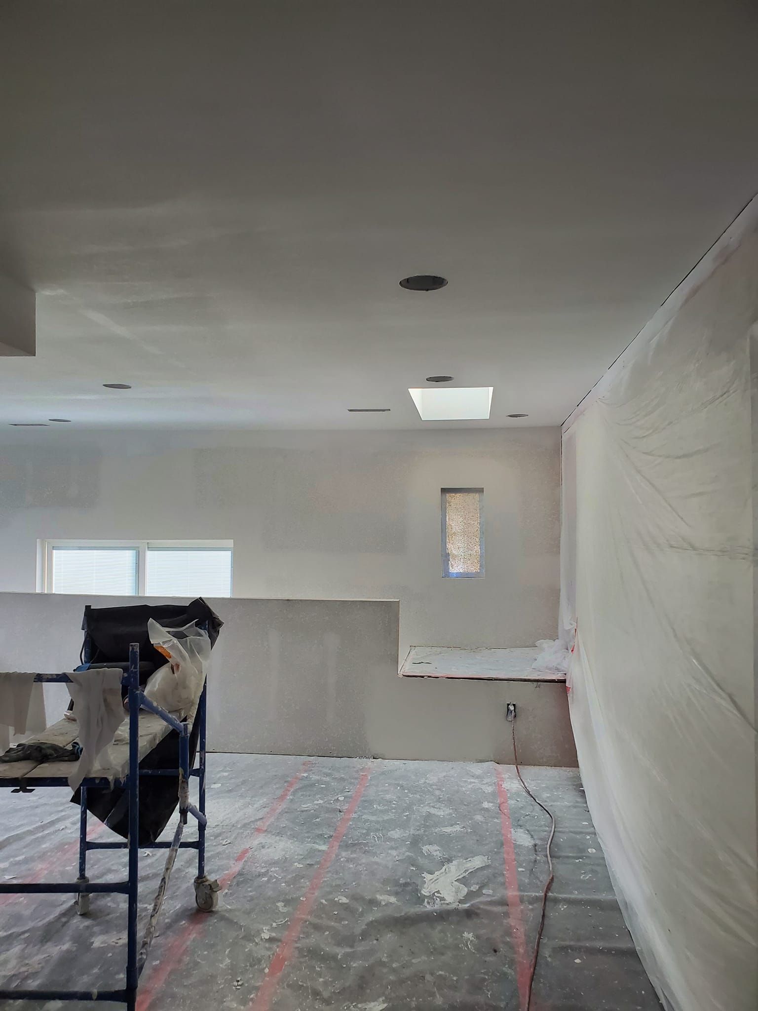 A room that is being painted with a scaffolding in the middle of it.