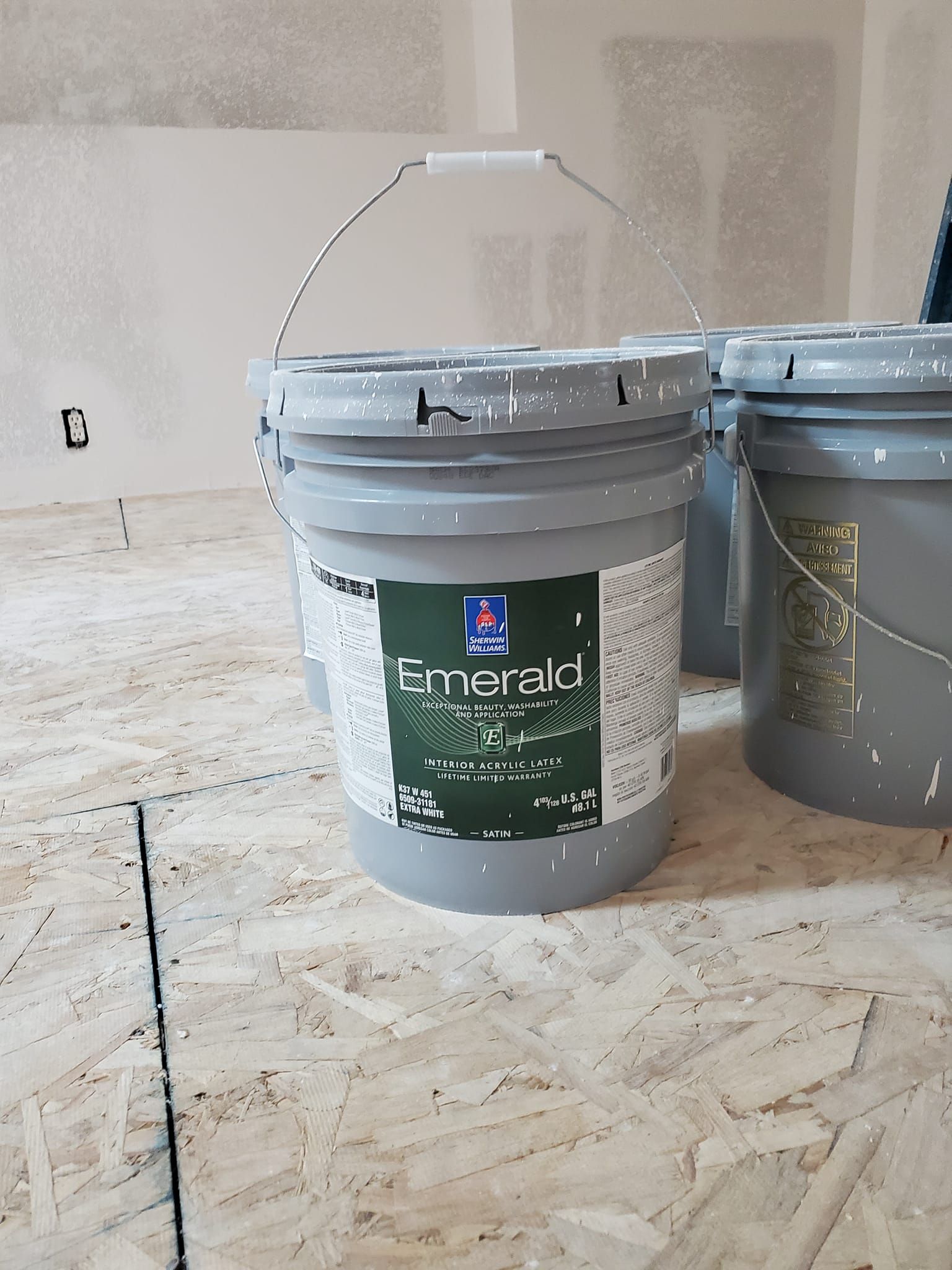 A bucket of emerald paint sits on a wooden floor