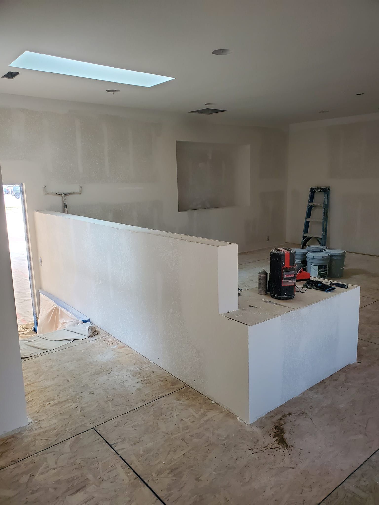 A room with a staircase and a ladder in it is being remodeled.