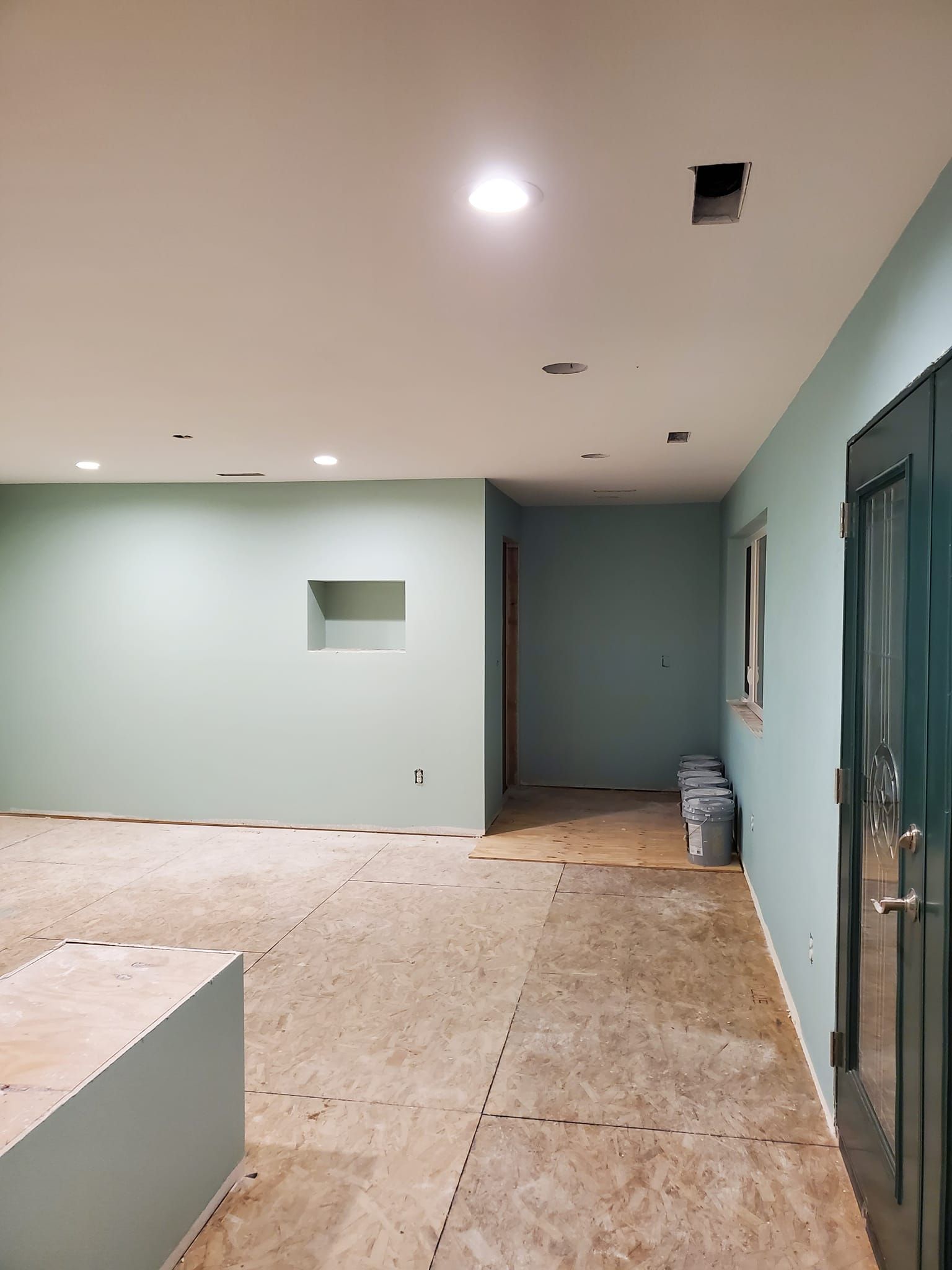 A room with green walls and a wooden floor is being remodeled.