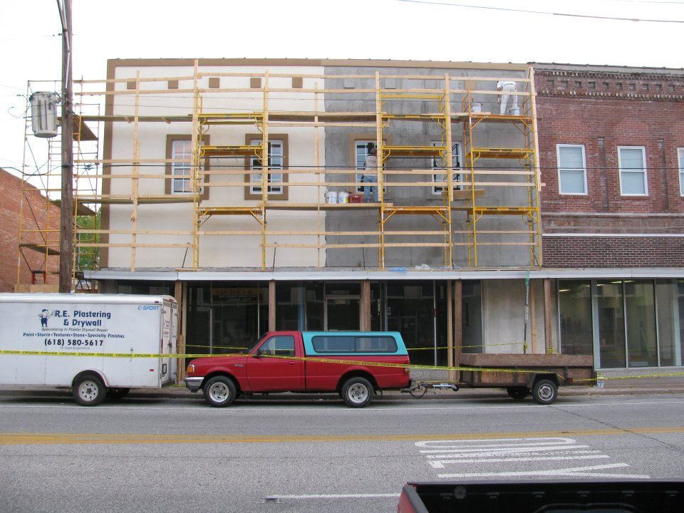 A red truck is parked in front of a building under construction
