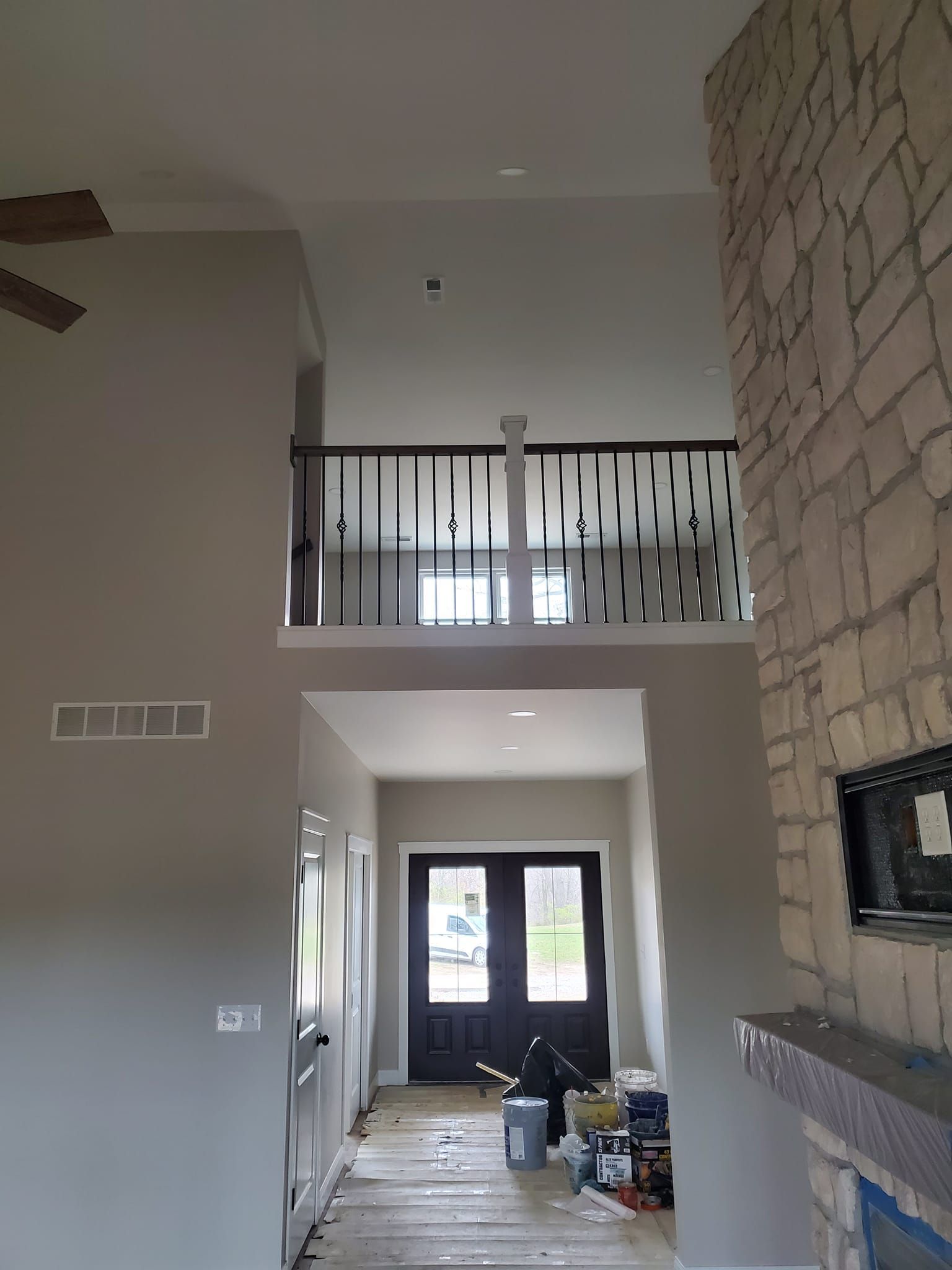 A living room with a balcony and a ceiling fan.