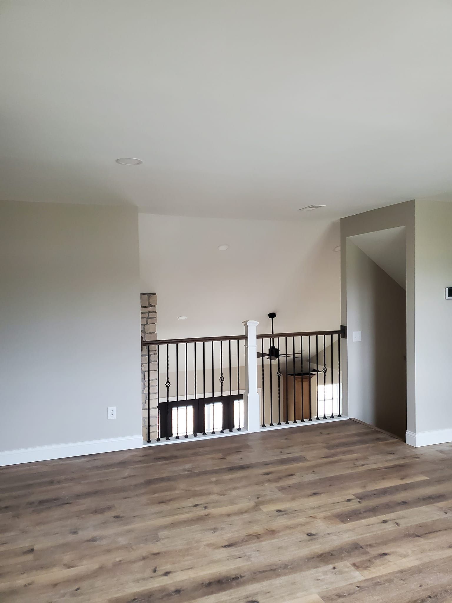 An empty living room with hardwood floors and a staircase.