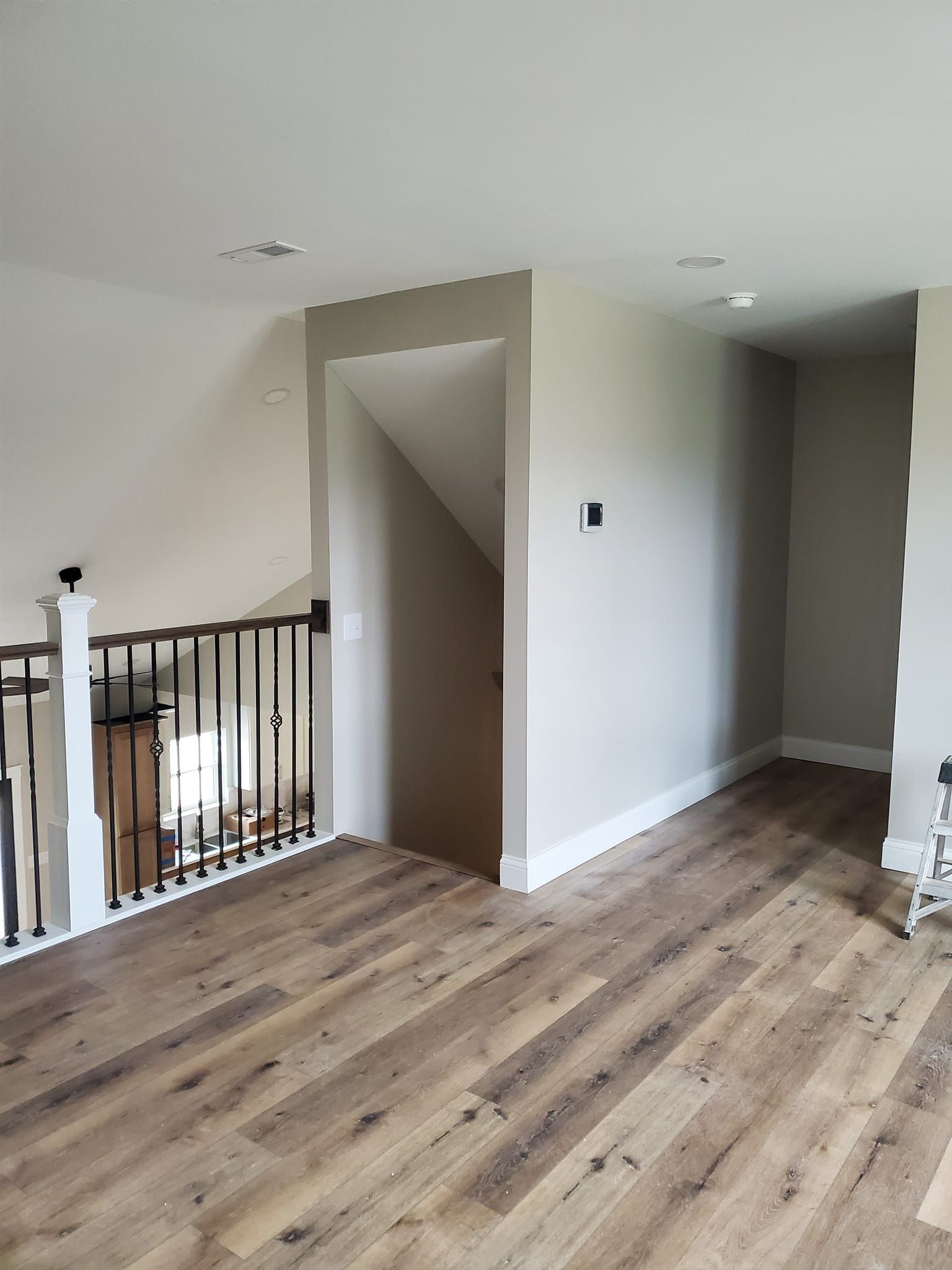 An empty room with hardwood floors and a staircase in the background.