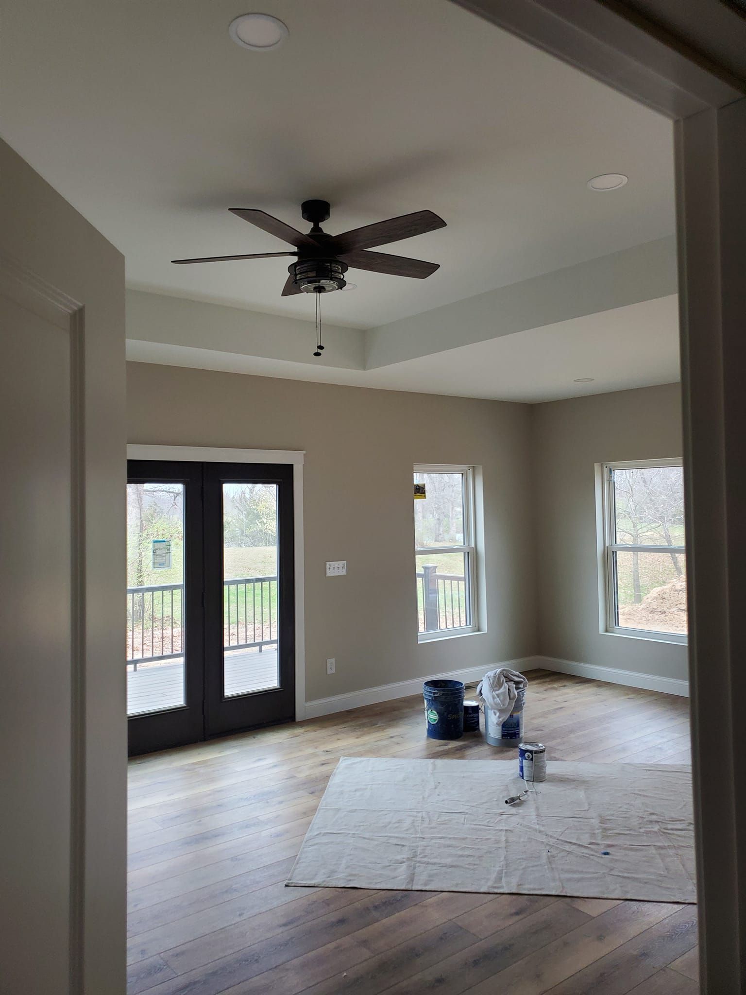 An empty room with a ceiling fan and a lot of windows.