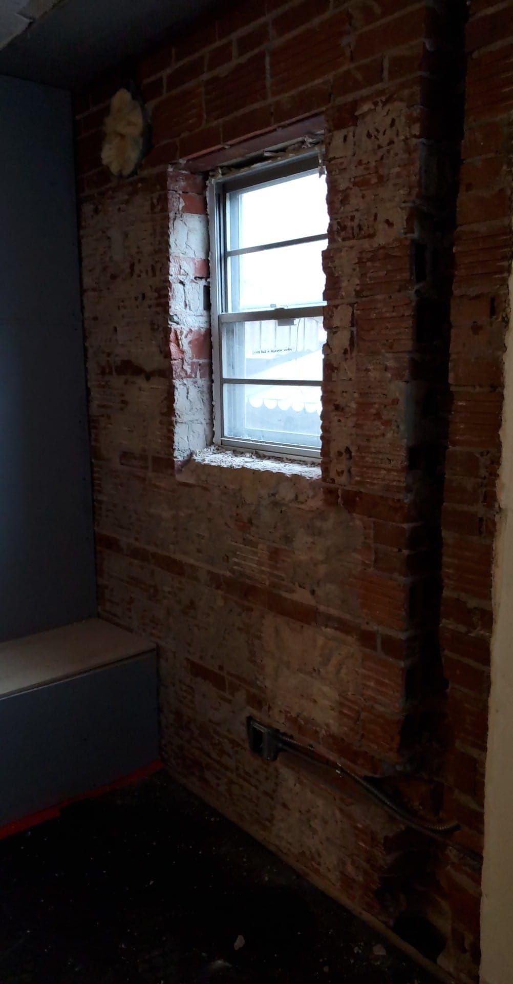 A room with a brick wall and a window in it.