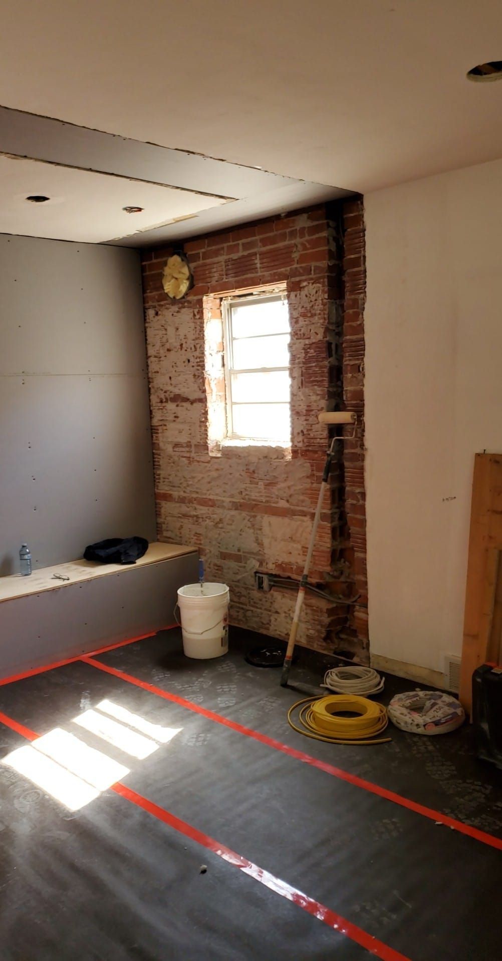 A room with a window and a bucket on the floor.