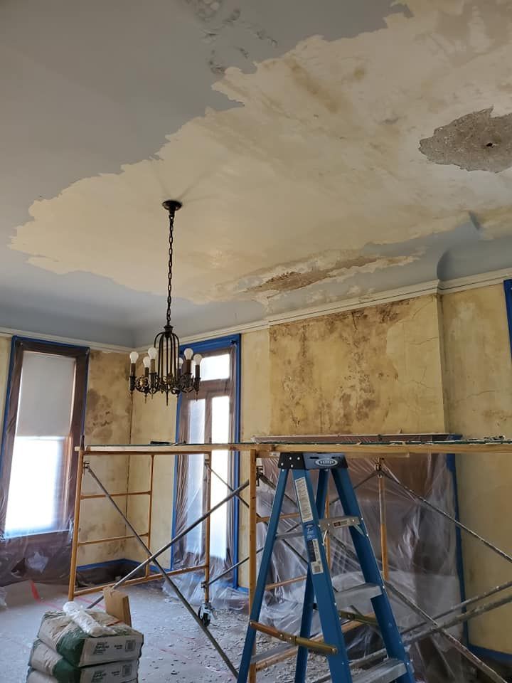 A room with a ladder and a chandelier hanging from the ceiling.
