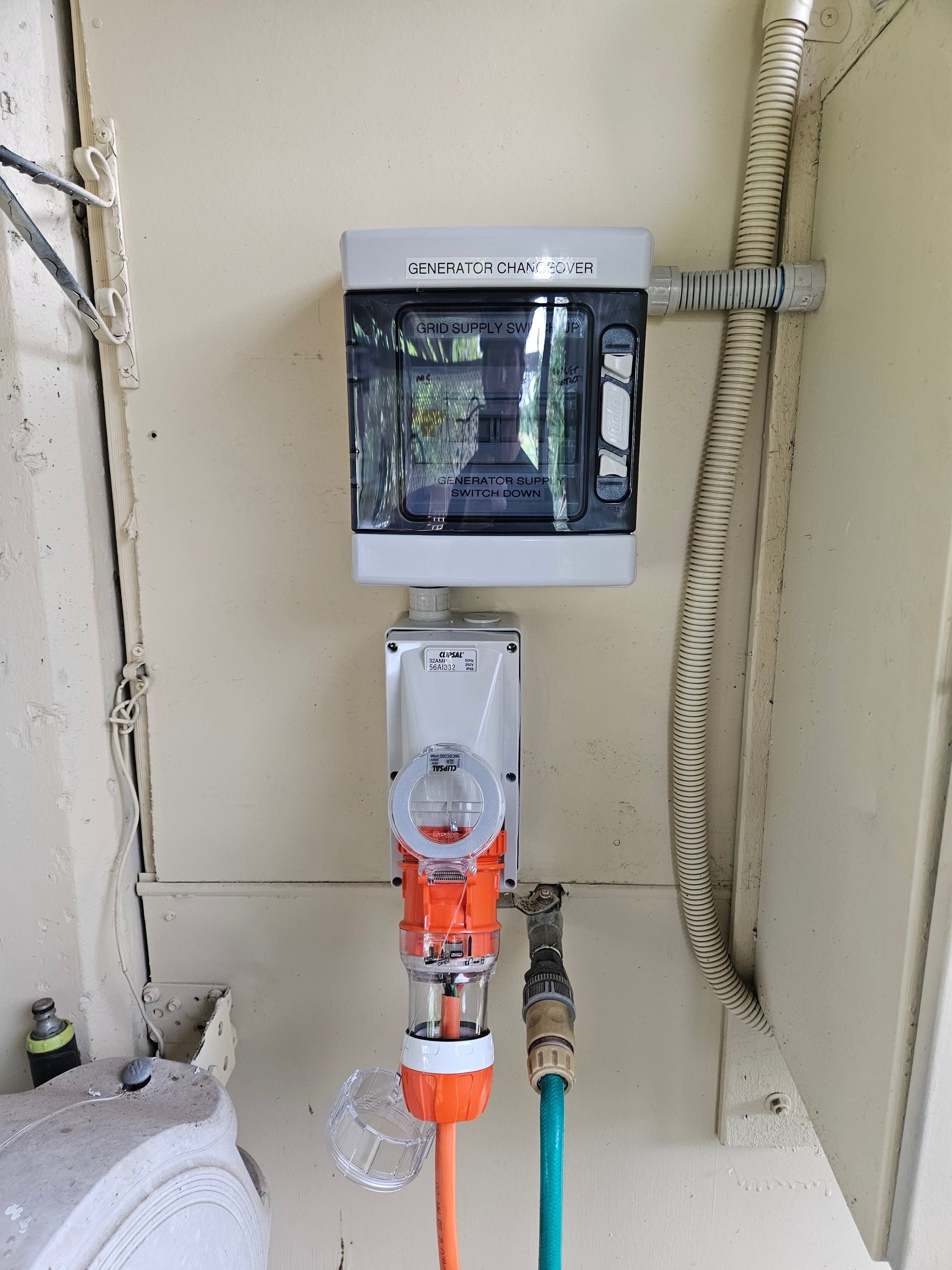Outdoor electrical outlet box with orange extension cord and hose connected to a water spigot. — Lit Energy in Seaforth, QLD