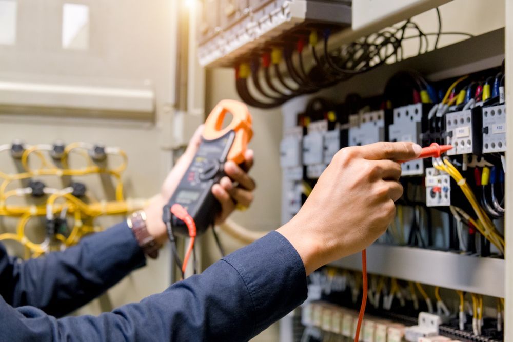 Electrician using a multimeter to test wiring in an electrical panel— Lit Energy in Bloomsbury, QLD