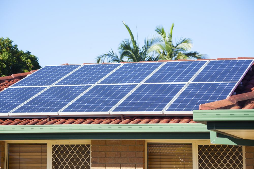 Solar panels on a residential rooftop, capturing sunlight; blue panels, red tile roof, sunny day— Lit Energy in Sarina, QLD