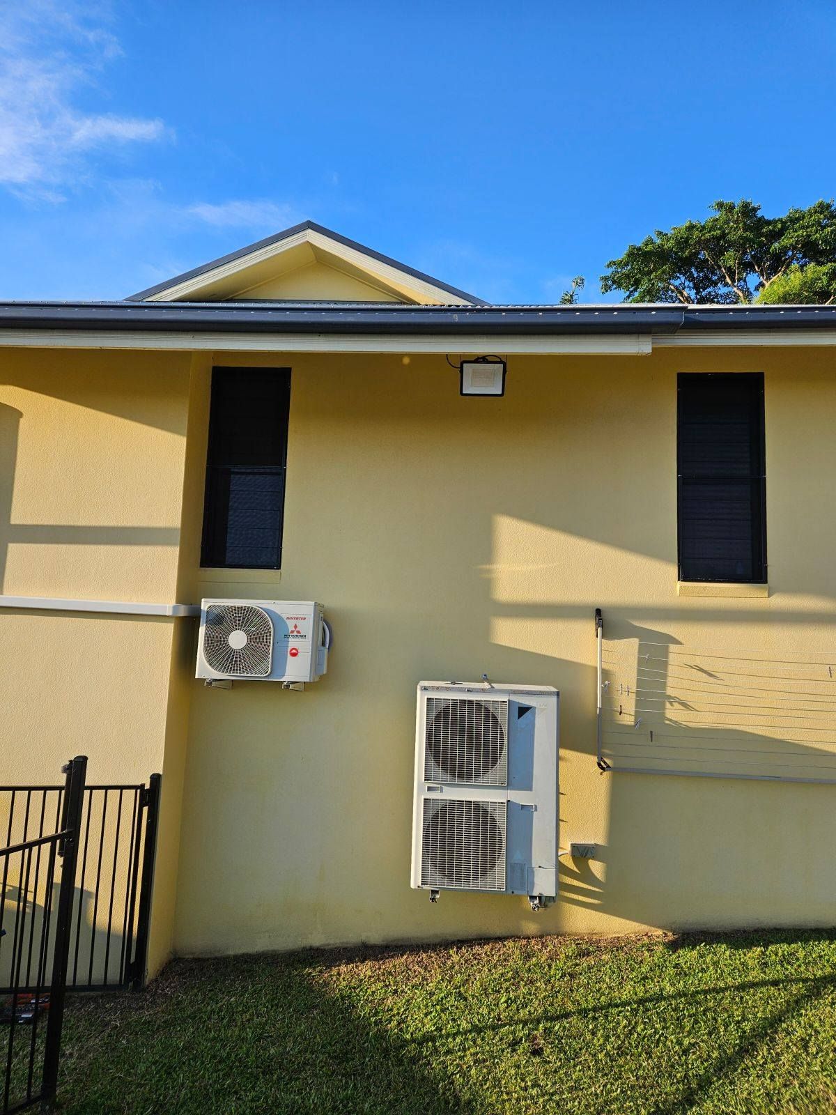 Yellow Building Exterior With Air Conditioning Units, Windows, And A Security Light — Lit Energy in Seaforth, QLD