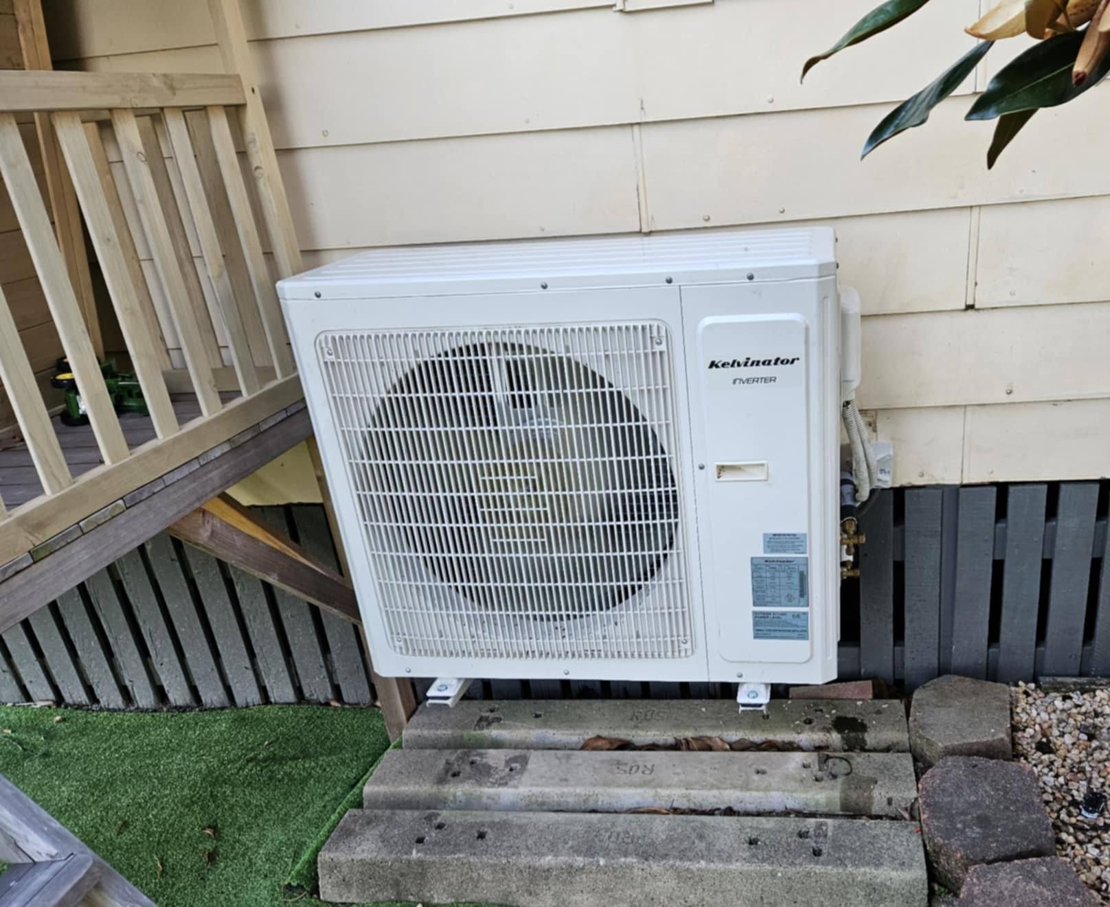 White Air Conditioner Unit On Concrete Steps Next To A House With Beige Siding — Lit Energy in Seaforth, QLD