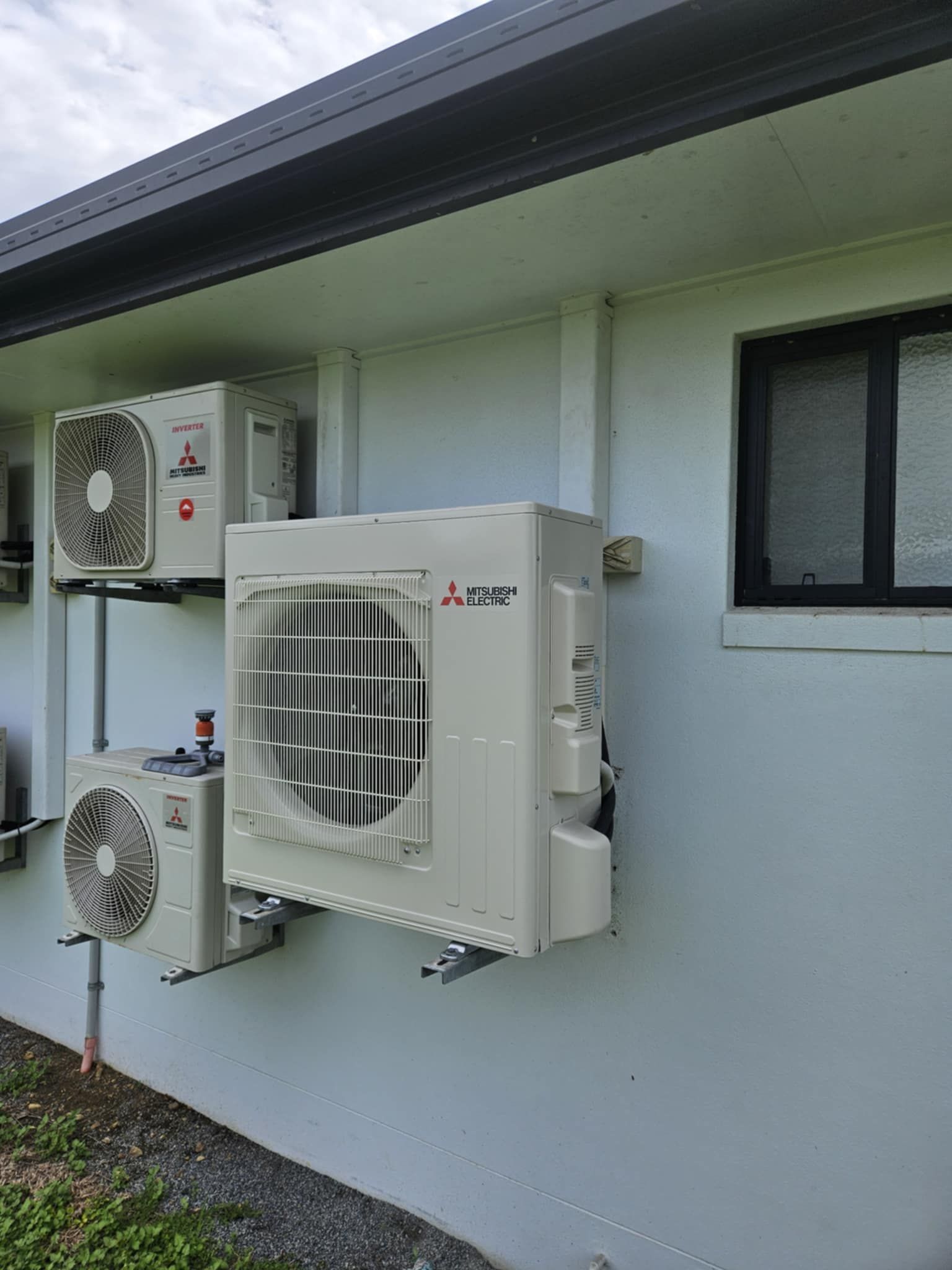 White Mitsubishi Ac Units Mounted On The Side Of A Light-colored Building, Near A Small Black Window — Lit Energy in Seaforth, QLD