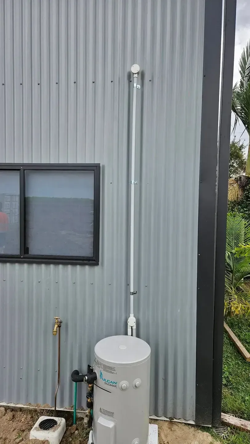 Water Heater With Exhaust Pipe on a Corrugated Metal Building Exterior — Lit Energy in Marian, QLD