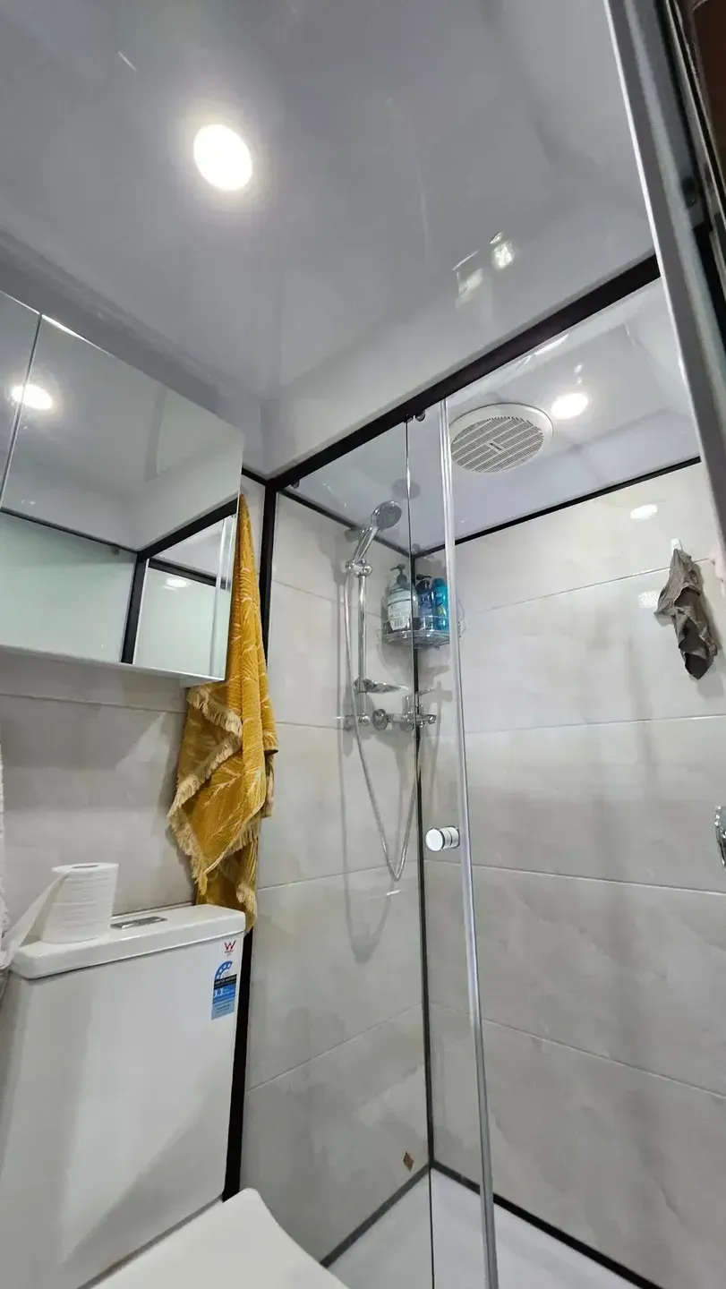 Small, Modern Bathroom With a Glass Shower, Toilet, and Mirror — Lit Energy in Seaforth, QLD