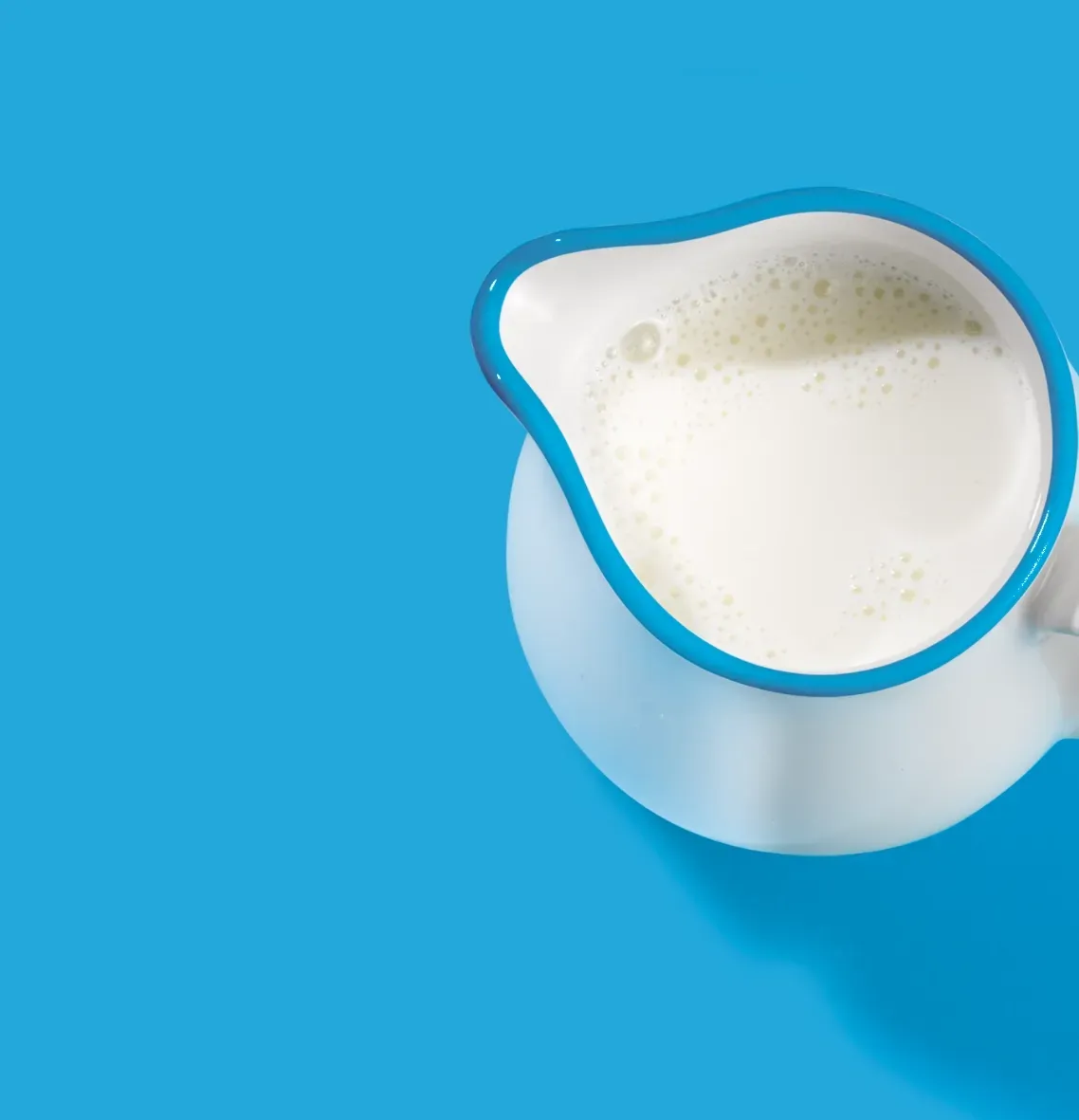 A pitcher of milk on a blue background.