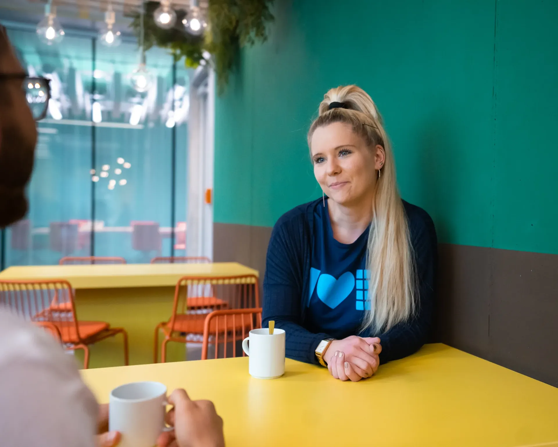 eine Frau sitzt an einem Tisch mit einem Mann und hält eine Tasse Kaffee .