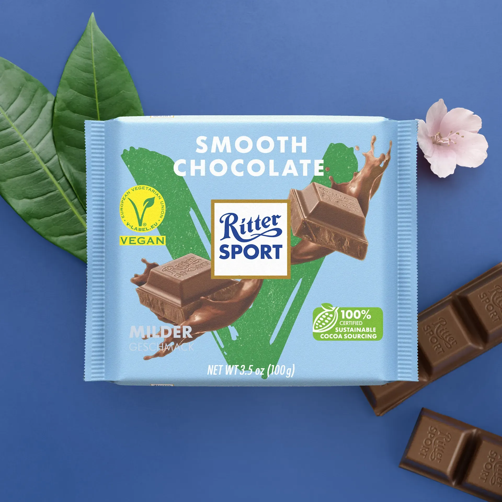 Ritter Sport Vegan Smooth Chocolate bar on blue background with leaves and flower.