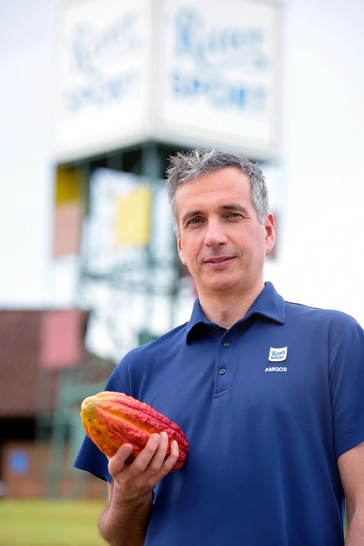 A man in a blue shirt is holding a cocoa pod