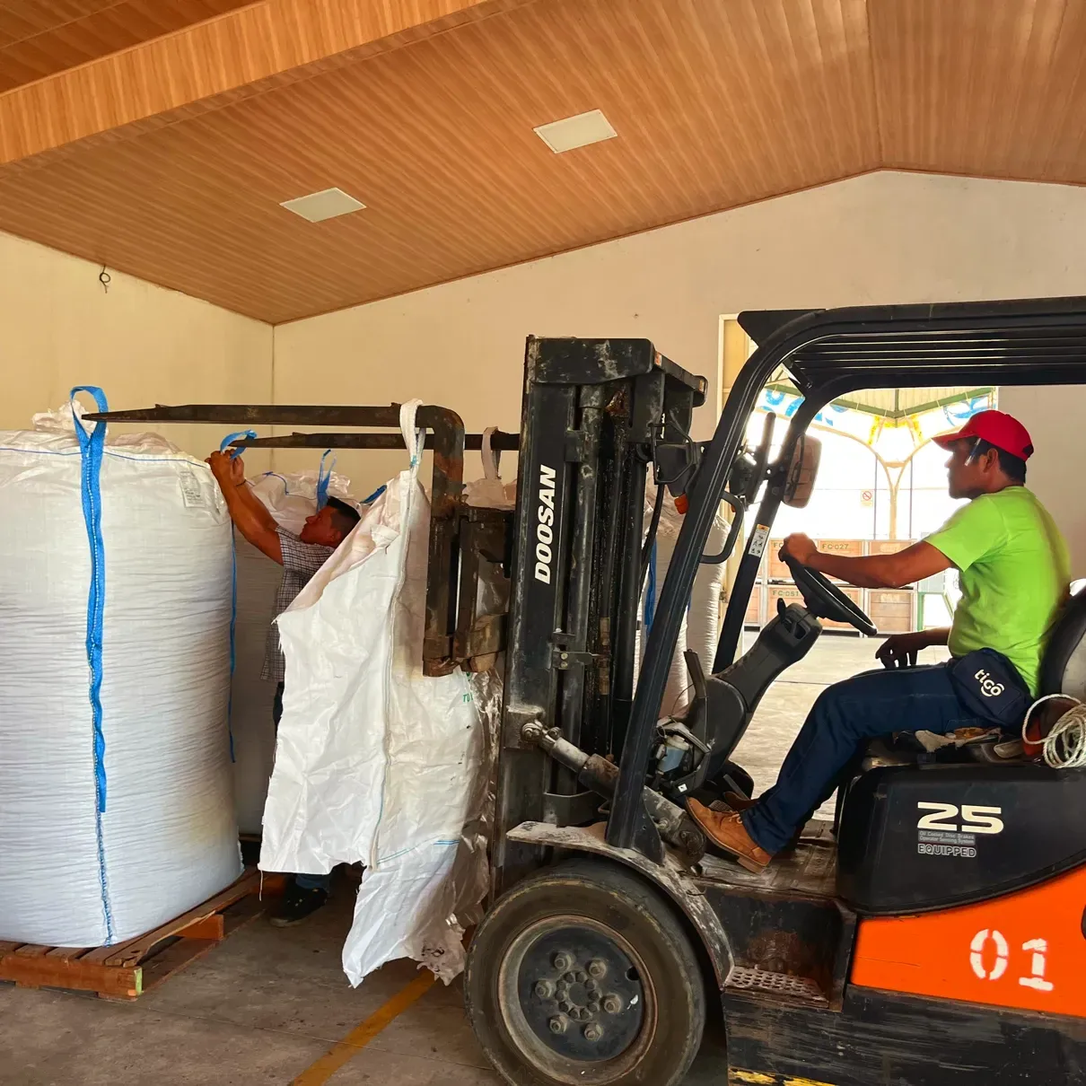 A man in a green shirt is driving a forklift