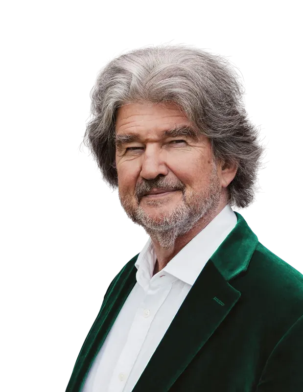 A man with gray hair and a beard is wearing a green jacket