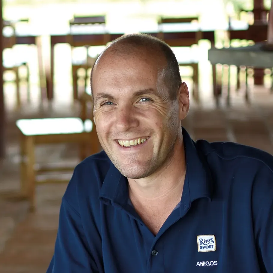 A bald man wearing a blue shirt that says Ritter Sport, smiles for the camera