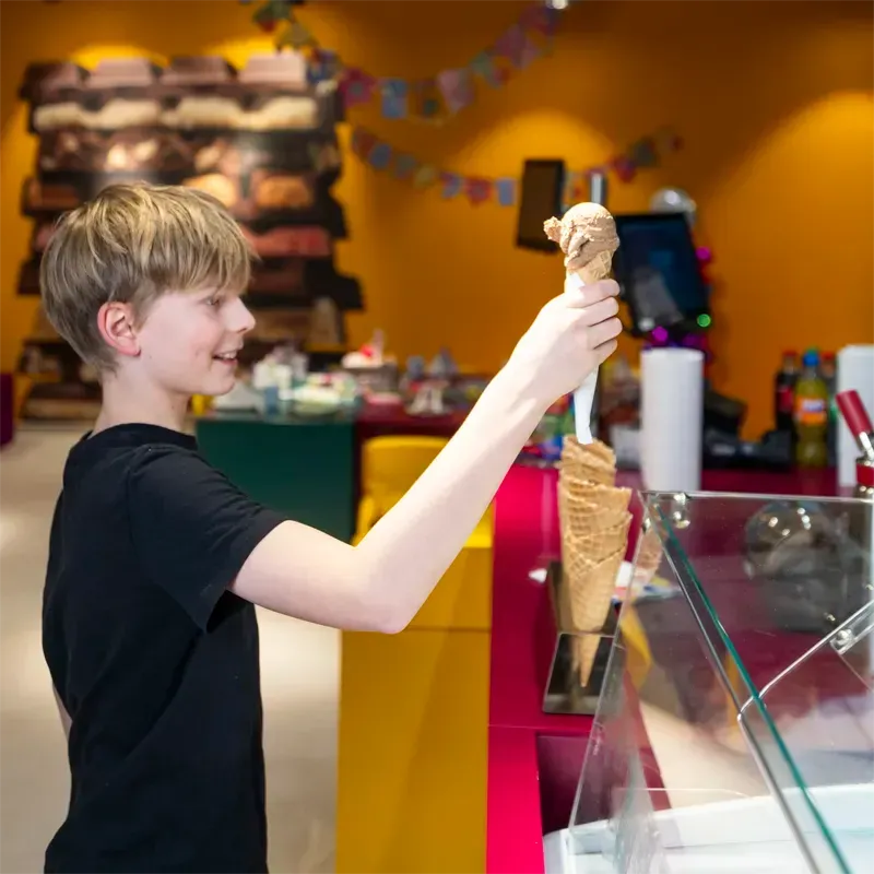 Kind bekommt an einer Theke ein Schokoladeneis
