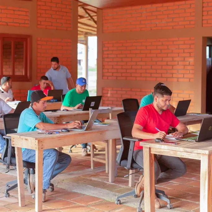 A group of men are sitting at tables with laptops