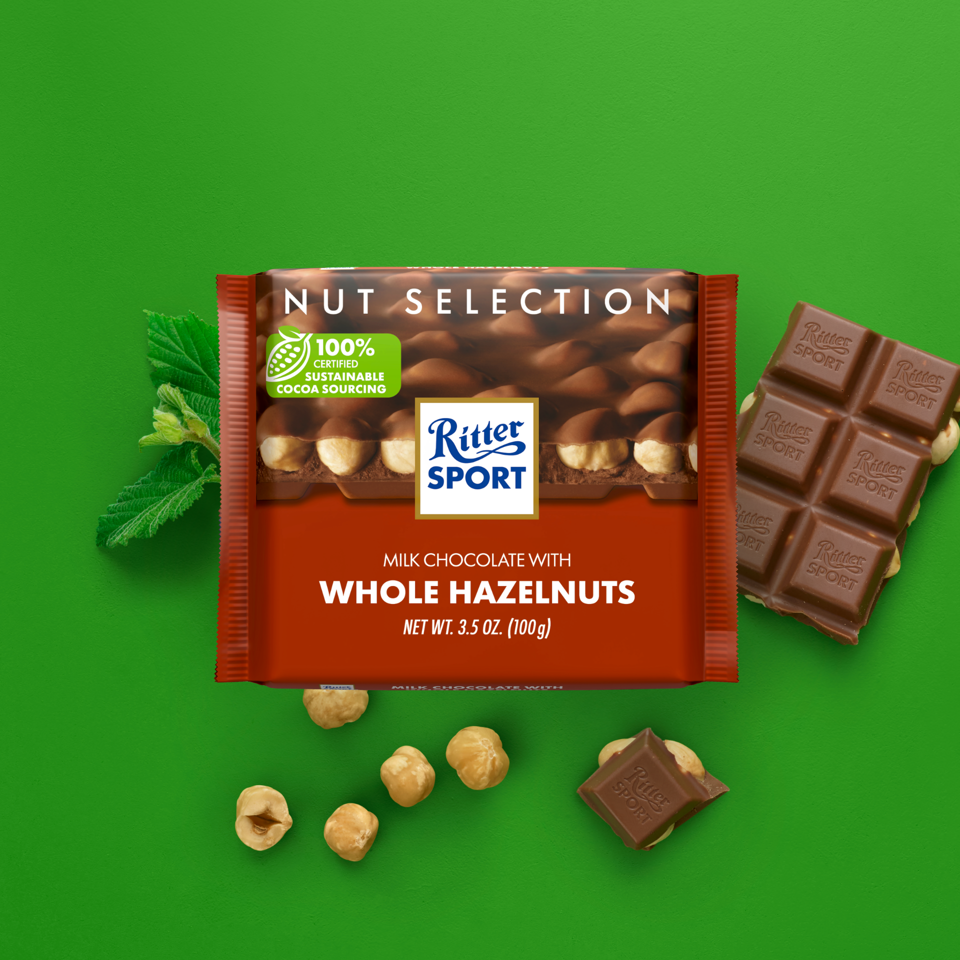 Ritter Sport chocolate bar with whole hazelnuts; package and pieces on green background.