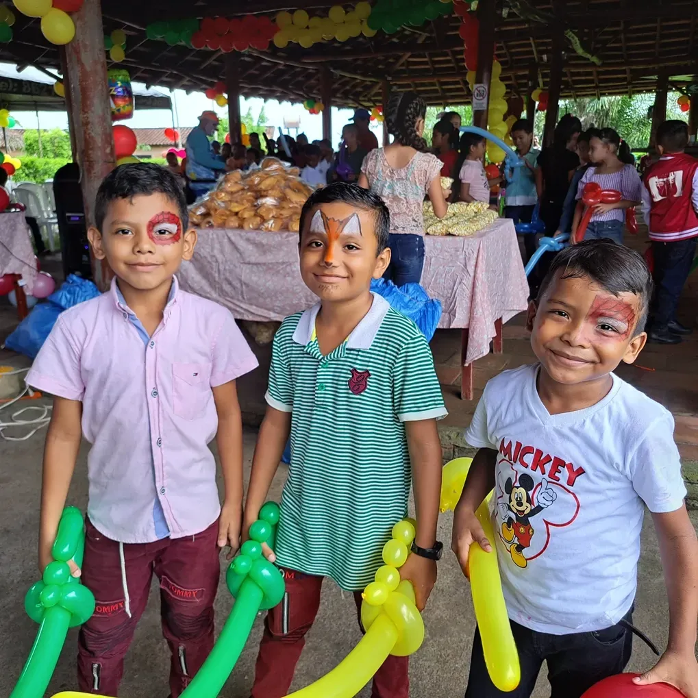 Three young boys with funny painted faces carrying ballon swords in their hands.