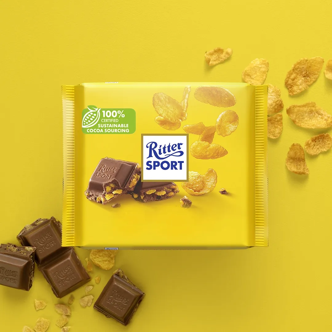 Ritter Sport chocolate bar with cornflakes on yellow background.