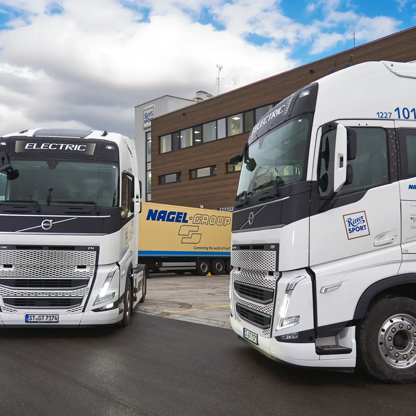 Two electro trucks are parked next to each other with Ritter Sport branding