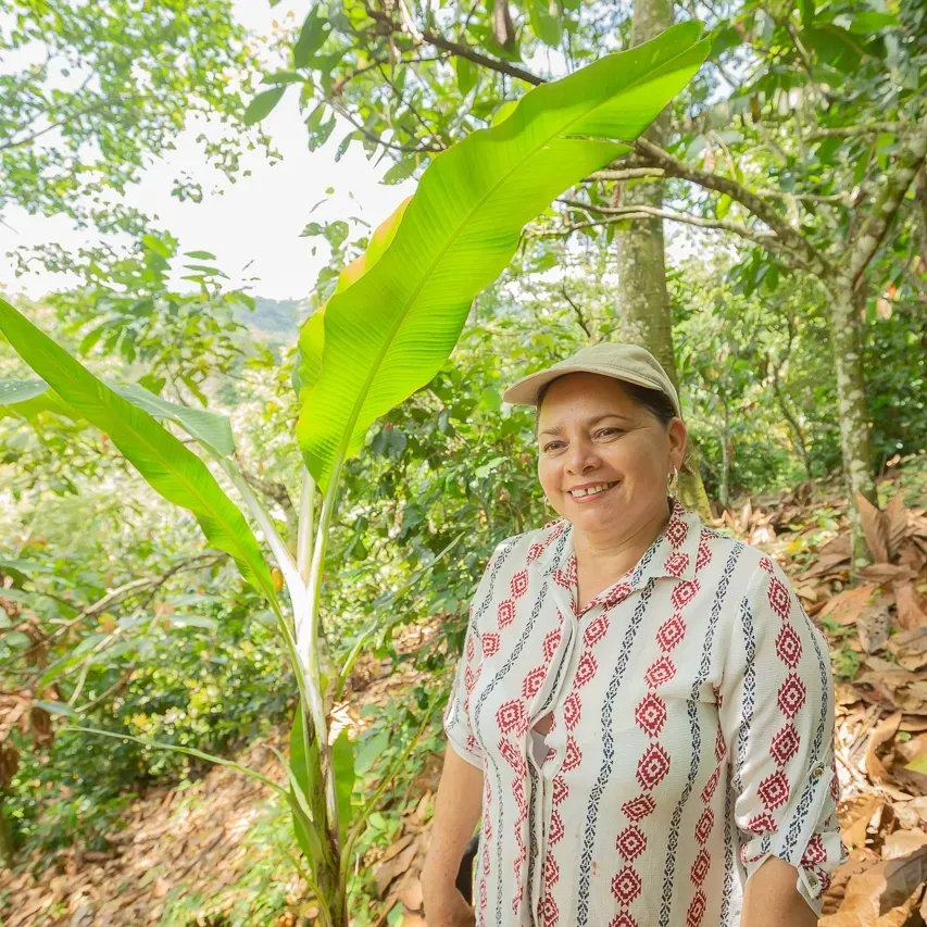 A woman in the woods next to a green plant