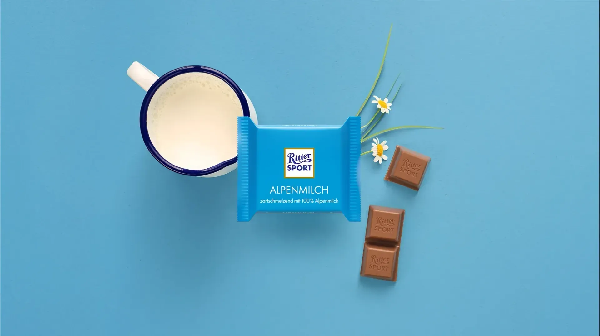 Verpackung einer blauen Schokoladentafel mit Nüssen, Schokoladenstückchen und dem Hinweis „55 % Kakaoanteil“ auf blauem Hintergrund