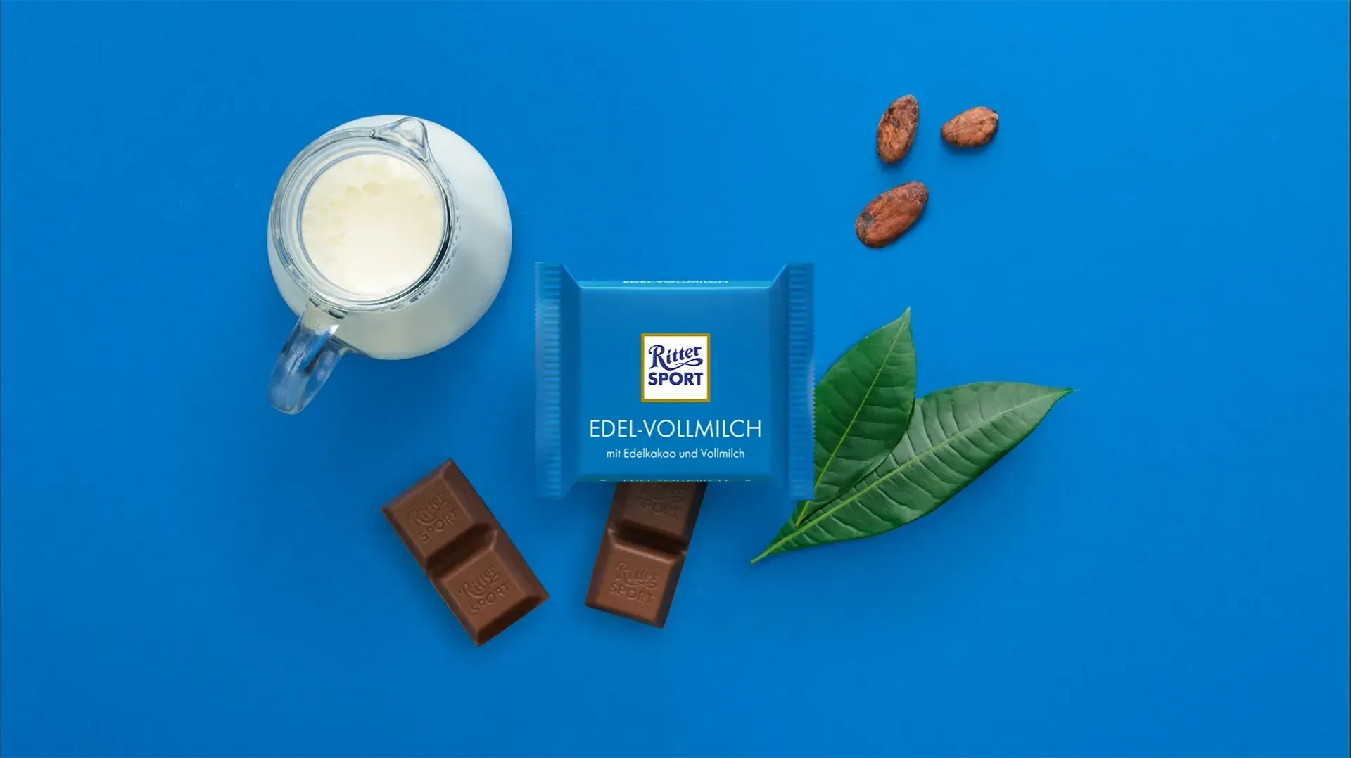 Verpackung einer blauen Schokoladentafel mit Nüssen, Schokoladenstückchen und dem Hinweis „55 % Kakaoanteil“ auf blauem Hintergrund