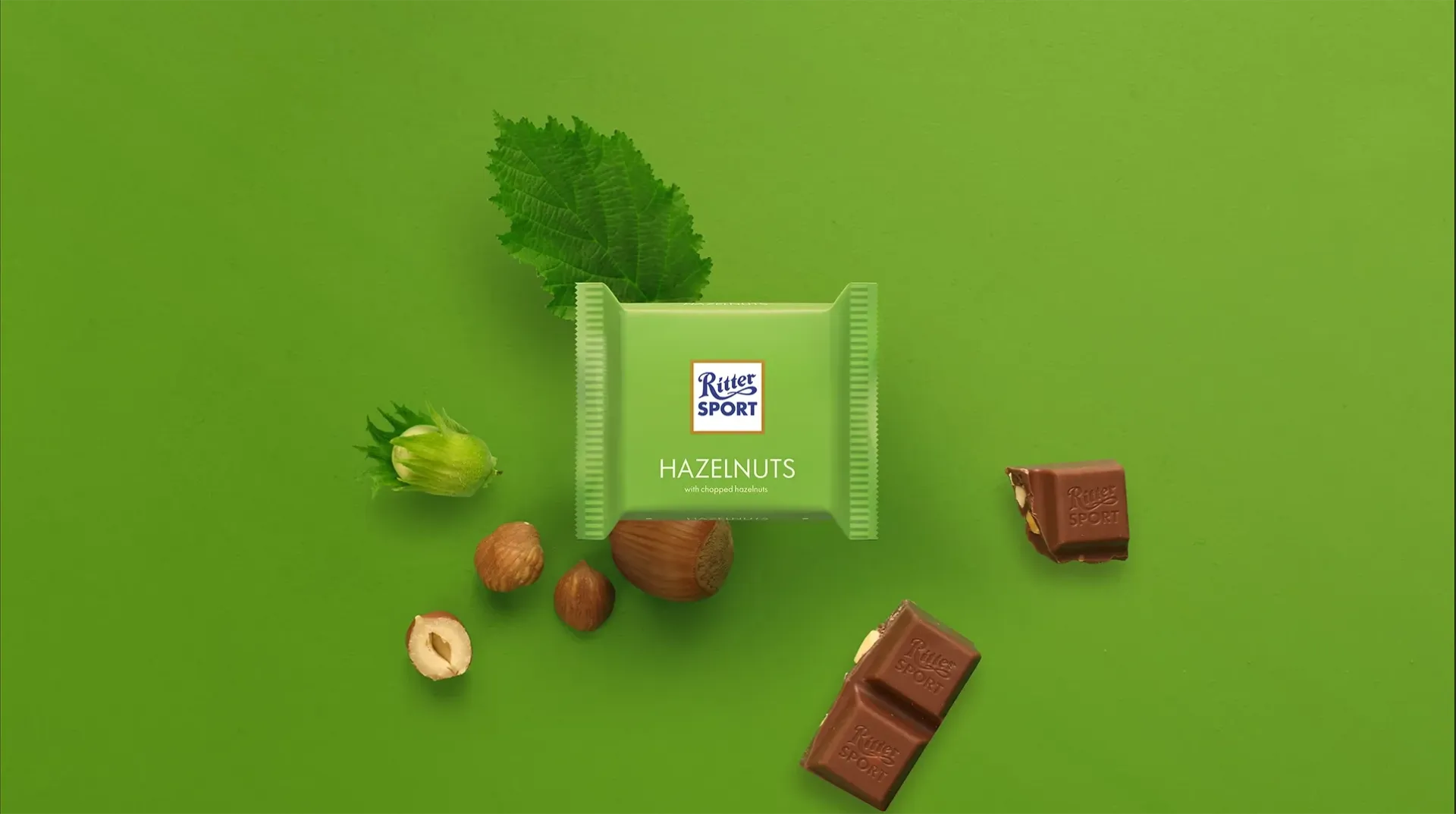 Ritter Sport chocolate bar packaging with cocoa beans, broken chocolate, and milk on a blue background.